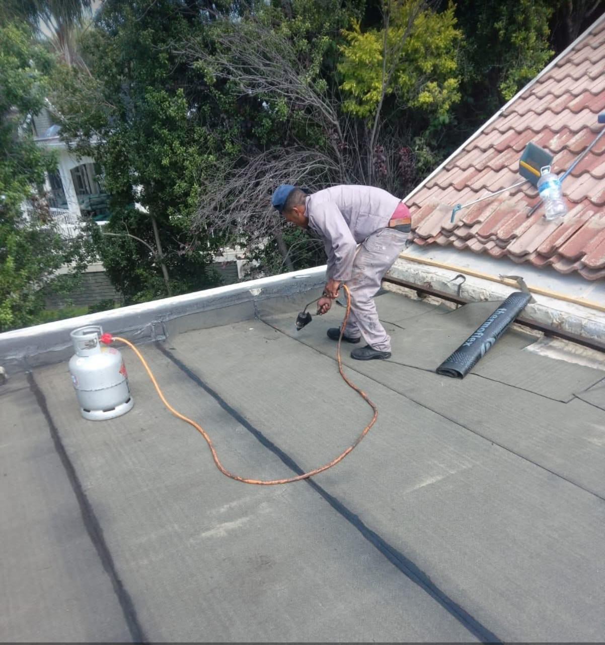 Torch-on waterproofing in progress on residential roof